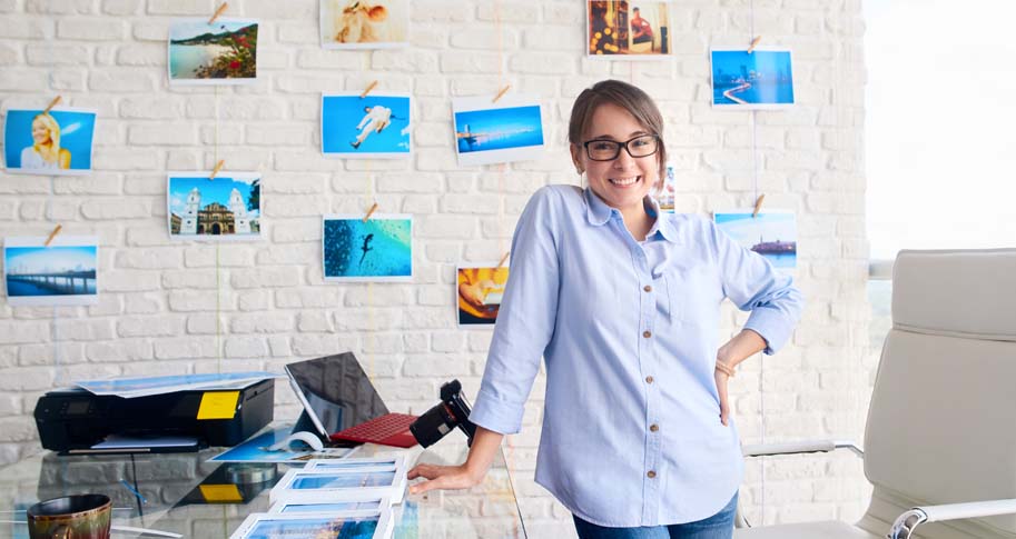 Woman standing at a desk with vibrant photos behind her