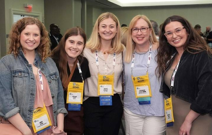 Five attendees at the WISE symposium wearing badges