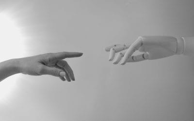 Black and white image with a real hand reaching towards a fake mannequin hand.