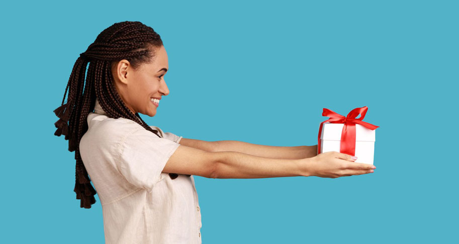 A woman holding a gift in her hands; Article: "Gift Giving May Be Easier Than You Think" by Mitchell Simpson with research by Daniel Villanova