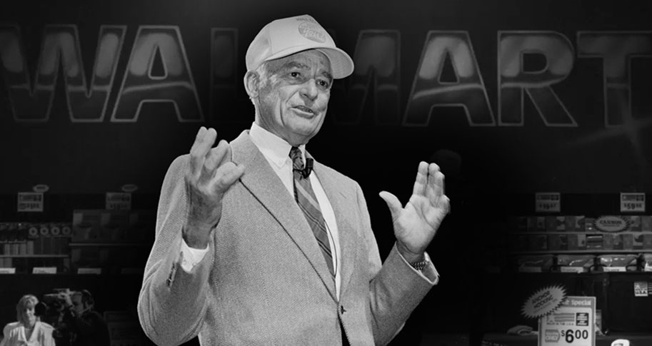 Black and white image of Sam Walton in front of a Walmart sign