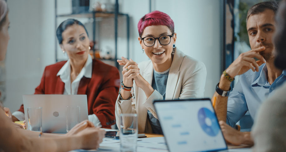 Office Meeting in Conference Room: Specialist with Short Pink Hair Talks about Firm Strategy with Diverse Team of Professional Businesspeople.