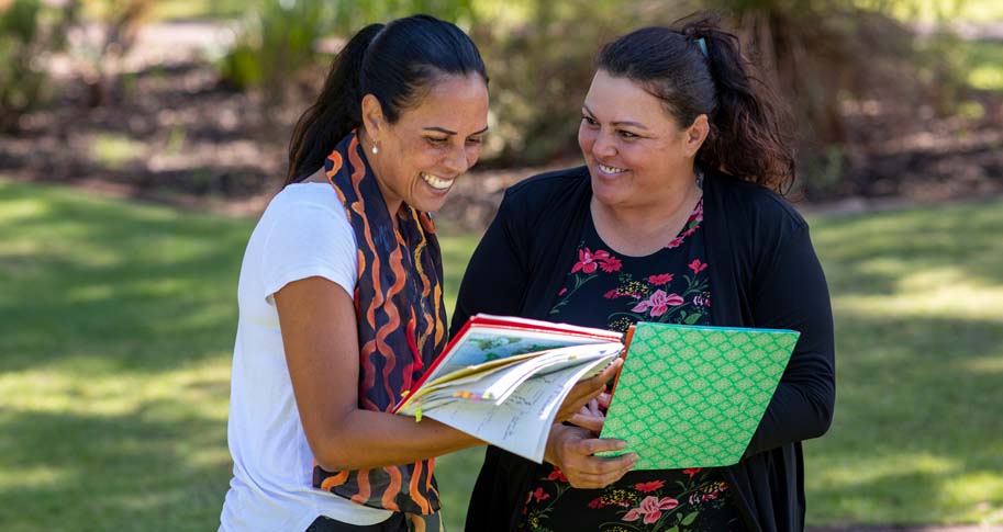 Two people reading through notebooks