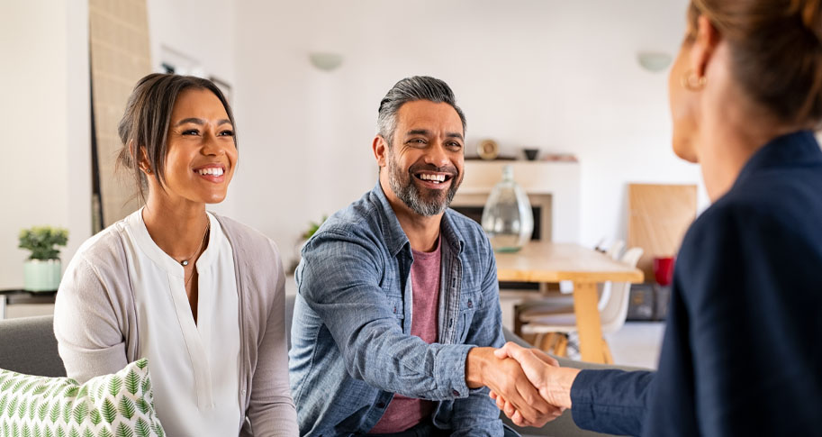 Smiling couple shaking hands with a businesswoman 