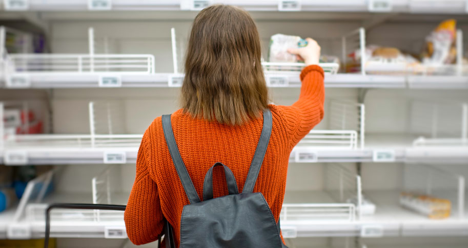 Woman shopping from empty grocery store shelves 