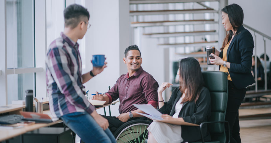 Male worker in wheelchair having cheerful discussion leading