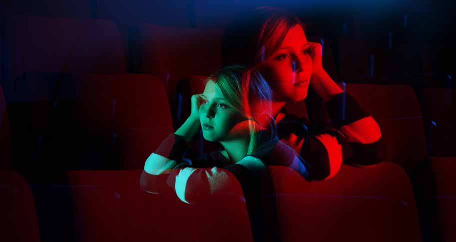 Girl sitting and thinking in theater style seats 