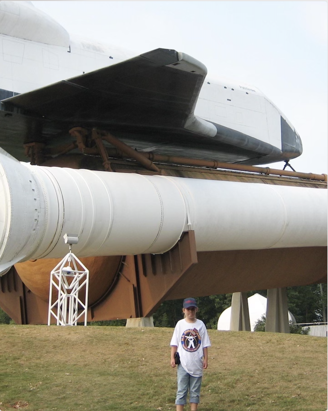 Raleigh as a child posing with a rocket at space camp.