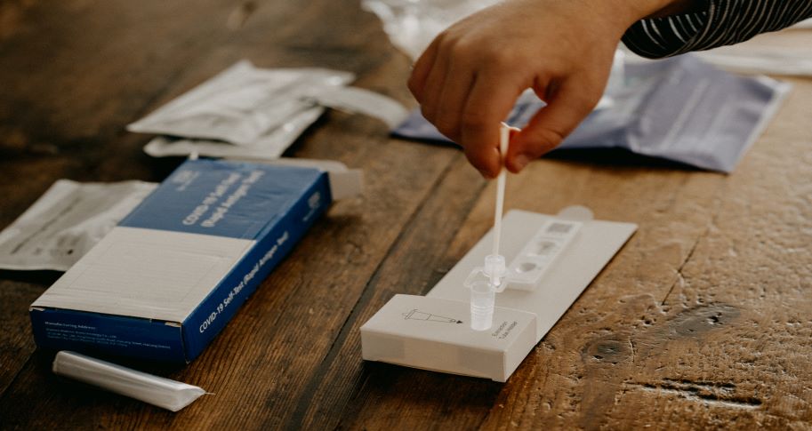 Image shows the hand of someone conducting an at-home Covid test.