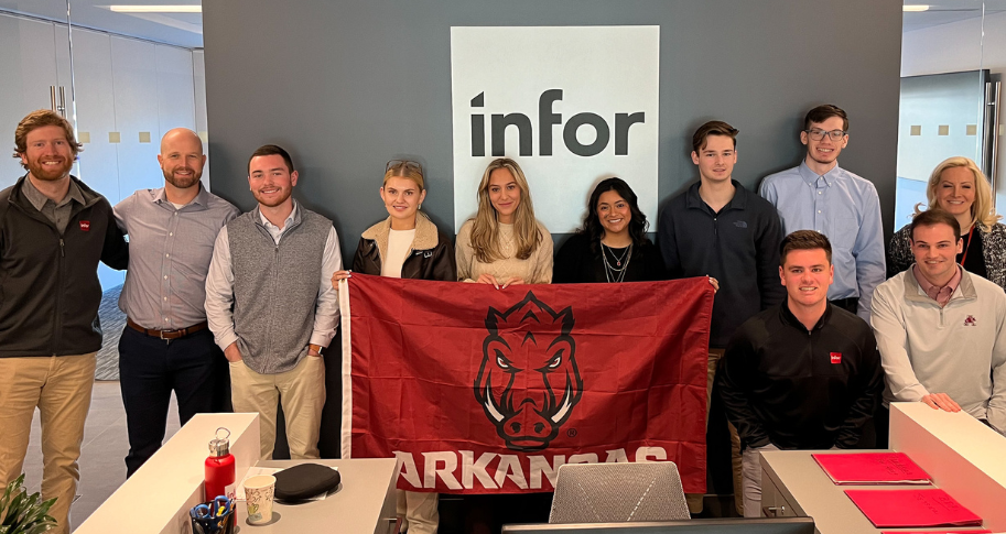 Students stand with a Razorback flag while shadowing at Infor