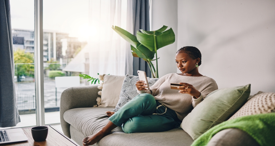 Woman completing an online purchase from her couch.