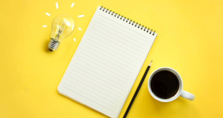 Coffee cup with paper, pencil and a lightbulb