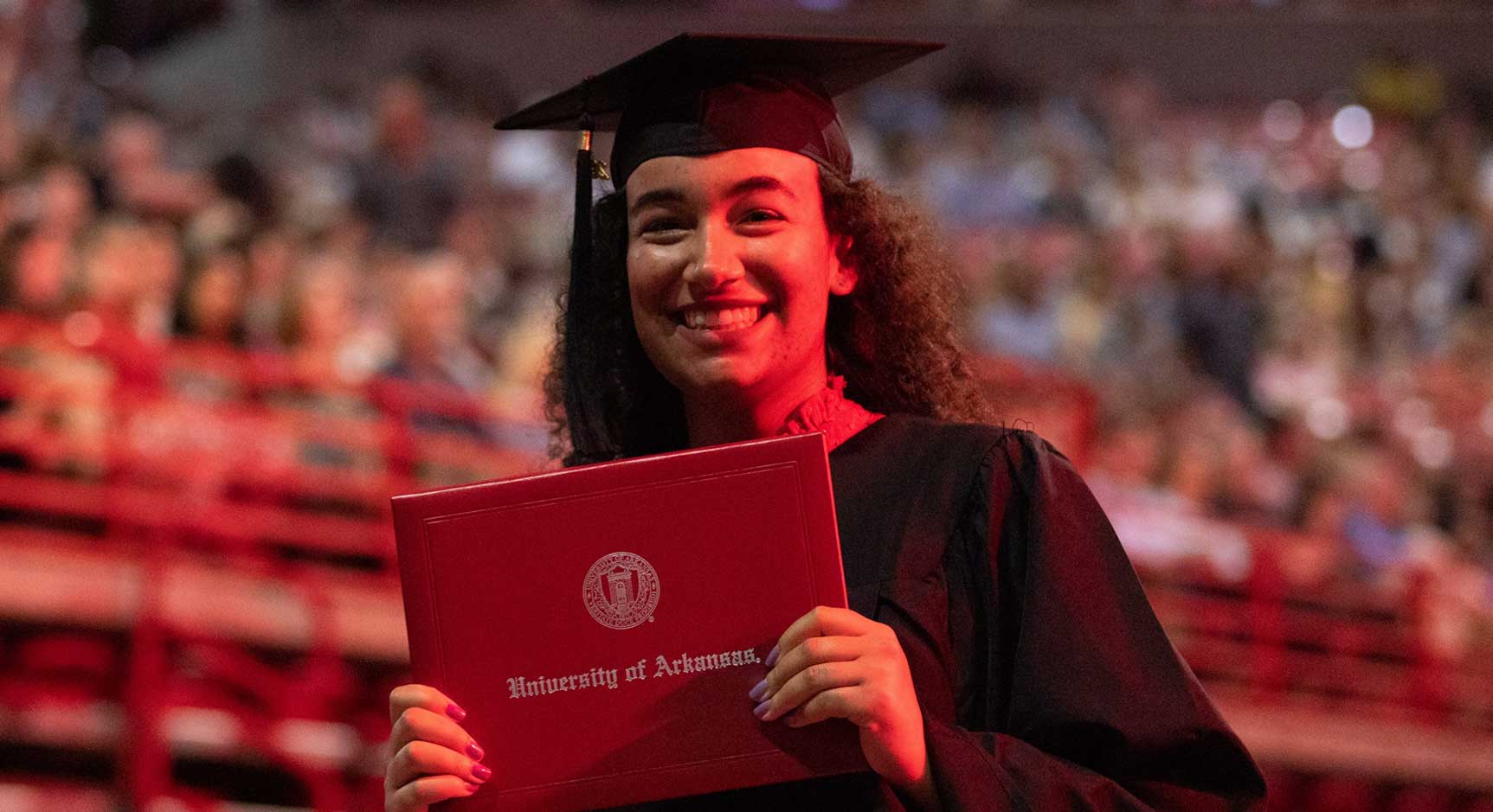 A Walton College student with a diploma at graduation